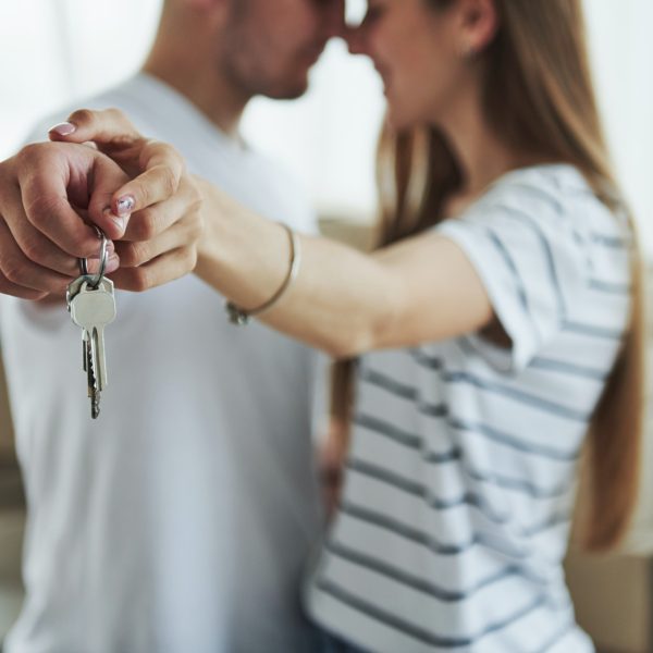 House keys. Cheerful young couple in their new apartment. Conception of moving